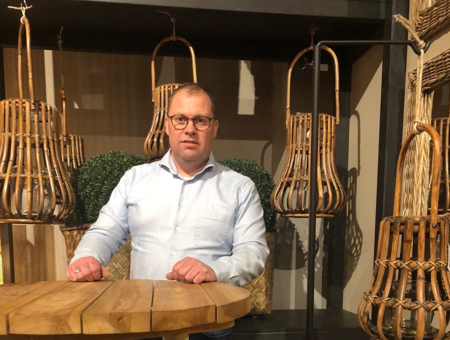 Aart-Jan Peeters staat naast een houten tafel met stoelen, met een neutrale achtergrond die de focus op de man legt.